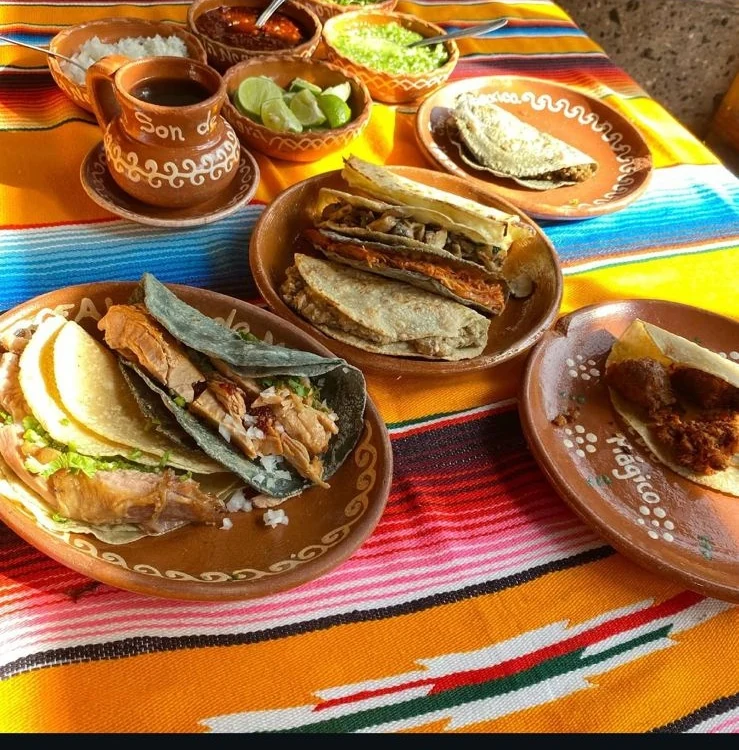 Tacos de barbacoa servidos en plato de barro sobre sarape mexicano